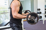 Muscular bodybuilder lifting heavy black barbell weight