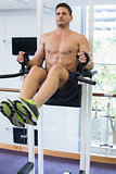 Shirtless bodybuilder doing leg lifts