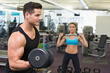 Muscular man and woman lifting weights