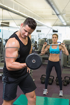 Muscular man and woman lifting weights