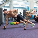 Bodybuilding man and woman lifting kettlebells in plank position