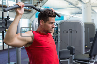 Handsome bodybuilder using weight machine for arms