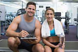 Female bodybuilder sitting with personal trainer smiling at camera