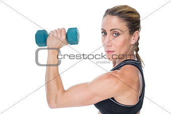 Female bodybuilder holding a blue dumbbell looking at camera