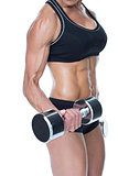 Female bodybuilder working out with large dumbbells mid section