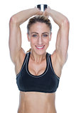 Female happy bodybuilder working out with large dumbbell behind head