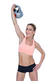 Female blonde crossfitter lifting kettlebell above head smiling at camera