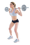 Strong female crossfitter lifting barbell behind head