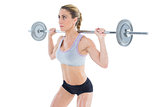 Strong female crossfitter lifting barbell behind head
