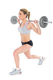 Serious female crossfitter lifting barbell behind head