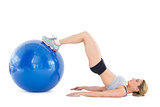 Fit woman lying on floor with legs on exercise ball