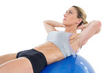 Fit woman doing sit ups on blue exercise ball