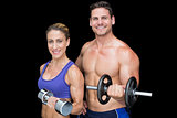 Crossfit couple posing with dumbbells smiling at camera