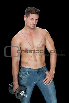 Muscular man holding large dumbbell in blue jeans