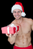 Smiling muscular man posing in sexy santa outfit offering gift