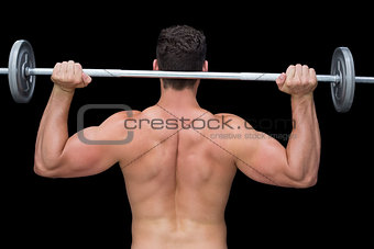Serious crossfitter lifting up barbell behind head