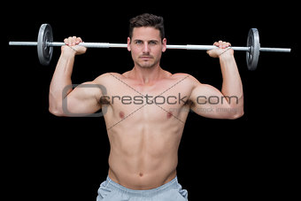 Serious handsome crossfitter lifting up barbell behind head