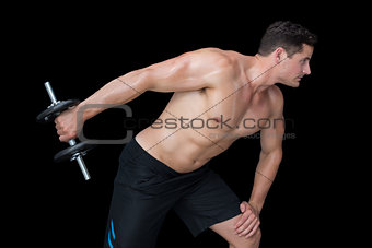 Strong crossfitter lifting heavy black dumbbell behind him