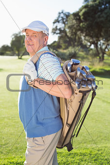 Golfer standing holding his golf bag smiling at camera