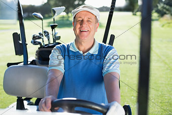 Happy golfer driving his golf buggy smiling at camera