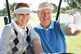 Happy golfing couple sitting in golf buggy taking a selfie