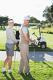 Happy golfing couple turning and smiling at camera