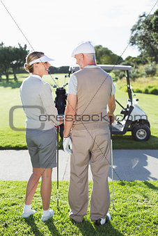 Happy golfing couple smiling at each other