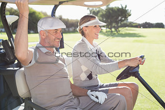 Happy golfing couple smiling in their buggy