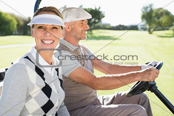 Happy golfing couple driving in their buggy