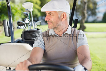 Happy golfer driving his golf buggy