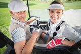 Golfing couple smiling at camera in their golf buggy
