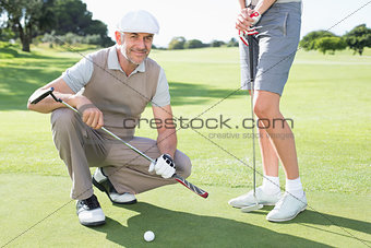 Golfing couple on the putting green with man smiling at camera