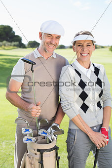 Golfing couple smiling at camera on the putting green