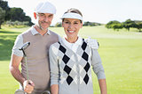 Golfing couple smiling at camera on the putting green