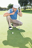 Serious golfer kneeling on the putting green