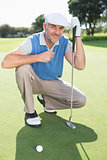 Smiling golfer kneeling on the putting green