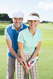 Golfing couple putting ball together smiling at camera