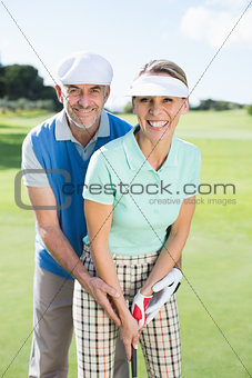 Golfing couple putting ball together smiling at camera
