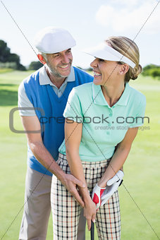Golfing couple putting ball together smiling at camera each other