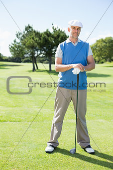 Cheerful golfer smiling at camera holding his club