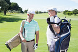Golfer friends chatting and holding their golf bags