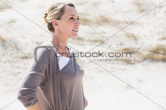Thinking blonde woman standing on the beach