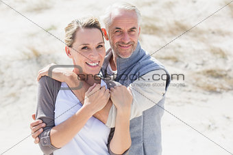 Happy hugging couple on the beach looking at camera