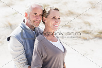 Happy hugging couple on the beach looking away