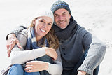 Attractive couple smiling at camera on the beach in warm clothing