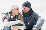 Attractive couple smiling at each other on the beach in warm clothing