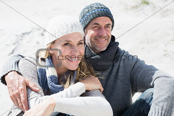 Attractive couple smiling on the beach in warm clothing