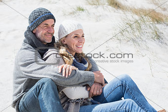 Attractive couple smiling on the beach in warm clothing