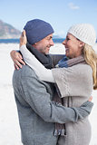 Attractive couple hugging on the beach in warm clothing