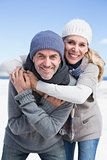 Attractive couple hugging and smiling at camera on the beach in warm clothing